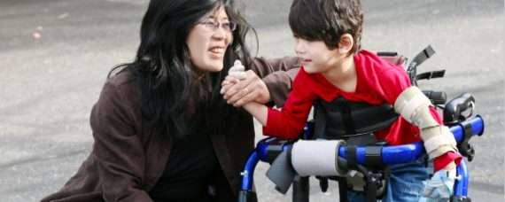 Teacher with an elementary school student standing in an specialized walker